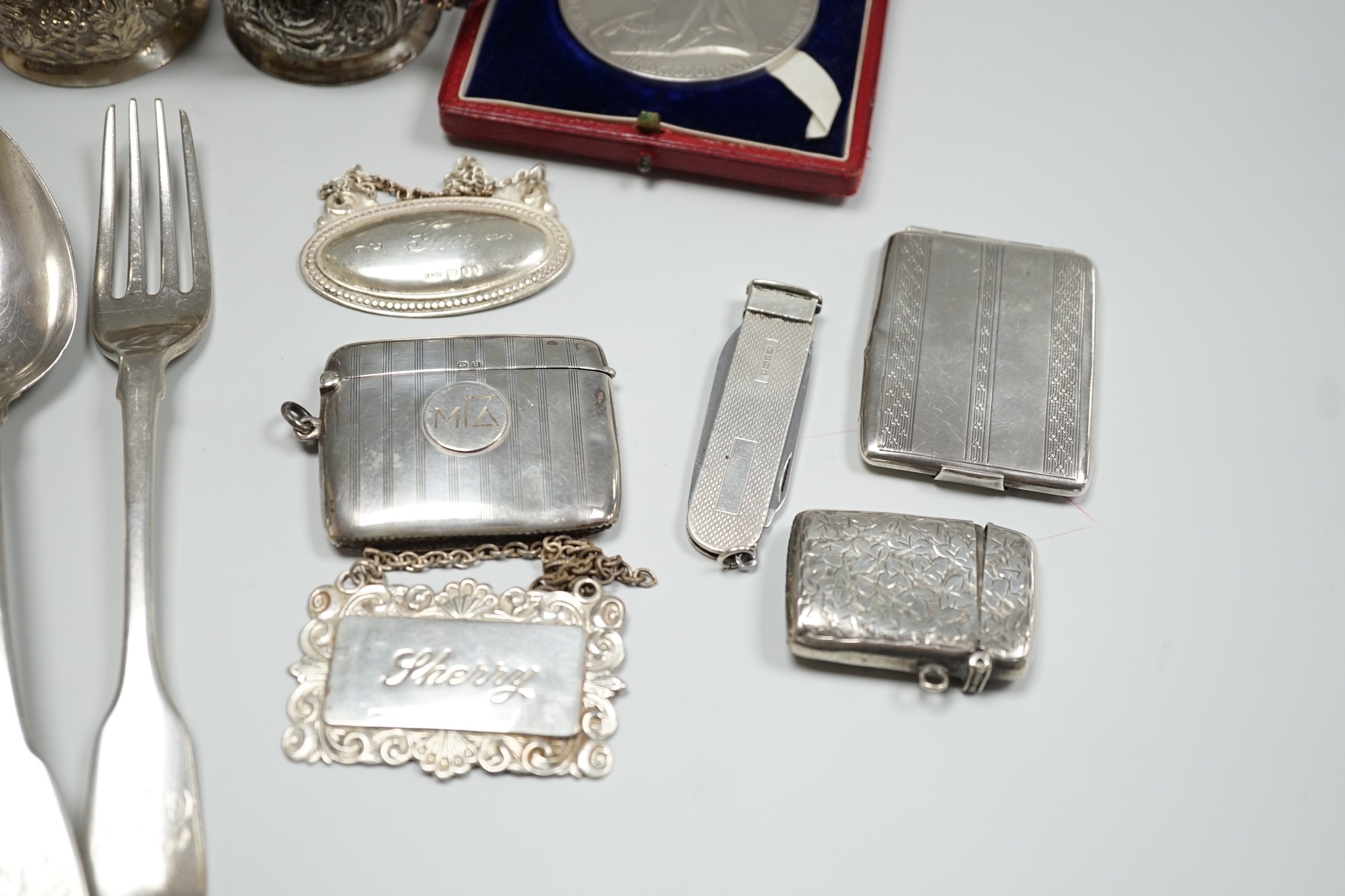 Sundry small silver including a George V goblet, cigarette case, vesta cases, flatware, wine labels and napkin rings including plated.